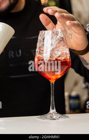 Bartender preparing on the counter Aperol Spritz, a classic refreshing Italian aperitif made mixing Aperol, Prosecco and sparkling Stock Photo