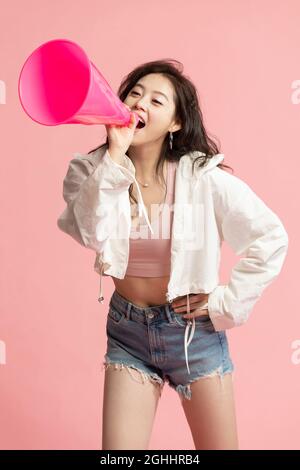 Studio shot of cute young woman shouting through megaphone Stock Photo