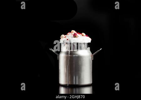 Milkshake with foam in metallic jar isolated on black background. Stock Photo