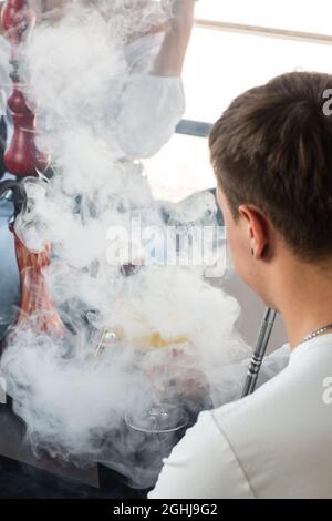 Close-up of man smoking traditional hookah pipe. man exhaling smoke. Hookah and sparks from coals. Shisha, spark, hookah sparks. Stock Photo