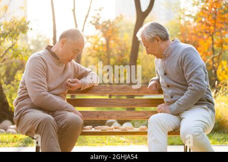 Cheerful senior men playing Chinese chess Stock Photo