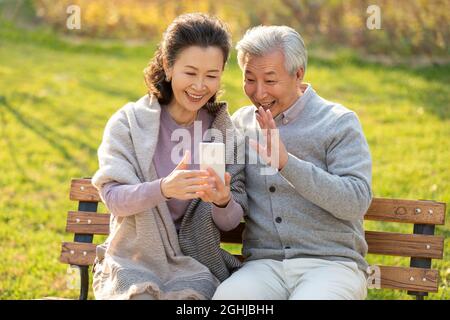 Cheerful senior couple using smart phone in the park Stock Photo