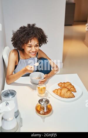 Cheerful attractive woman having oatmeal for breakfast Stock Photo