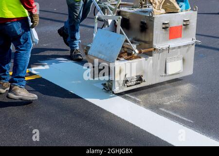 Workers paint new road surface stripes on new asphalt. Stock Photo
