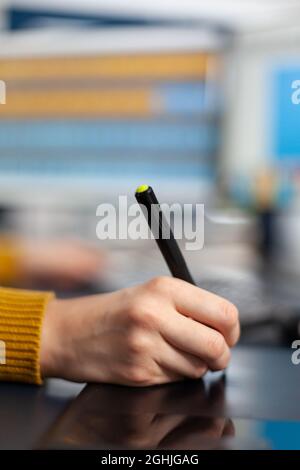 Close up hand of young woman photo drawing on graphic tablet editing customer photo on computer with two monitors. Photographer holding stylus pen retouching assets in photography agency Stock Photo