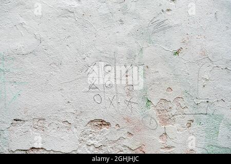 Tic tac toe or noughts and crosses game scratched on old concrete white wall, texture, urban background, space for text Stock Photo