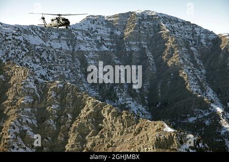 A UH-60 Blackhawk helicopter flies above the Afghan countryside. This image was taken from a CH-47 Chinook helicopter while flying over Paktika province, Afghanistan, Dec. 18. Stock Photo