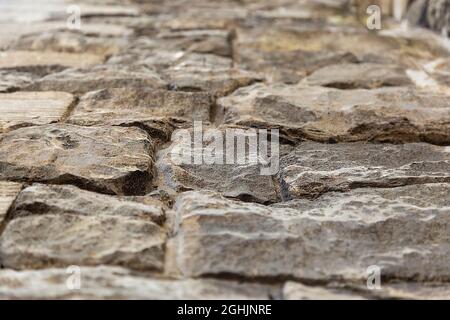 The road is made of old cobblestones, photographed from below, in focus in the center, a place for text. Stock Photo