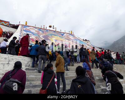 People paying respects at foot of giant Thangka painting of the Maitreya Buddha at Drepung Monastery, Mount Gephel, Lhasa, Tibet - Aug 2014 Stock Photo