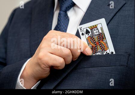Poker king card in the hand of a business man in a suit. Stock Photo