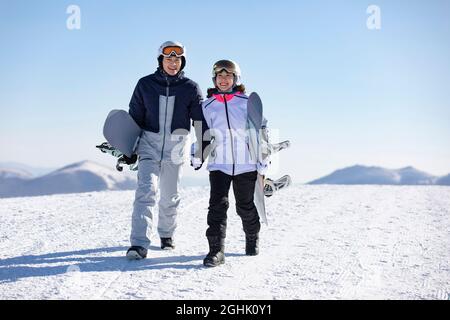 Young couple walking with snowboards on the snow Stock Photo