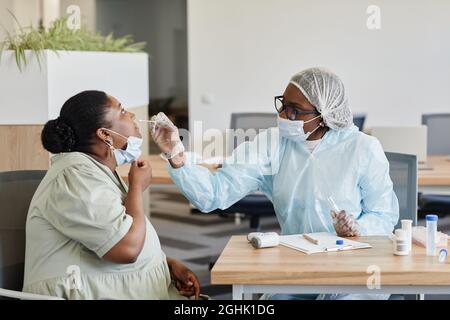 Female doctor in protective suit taking nasal swab to collect samples for laboratory coronavirus test Stock Photo