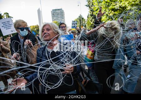 Warsaw, Poland. 06th Sep, 2021. Activists tied up with a wire to symbolize the barbed wire fence on the border with Belarus are seen blocking the street.The Polish Parliament today evening formally approved the state of emergency in two regions bordering Belarus - the first order of its kind since Poland's communist days. Many of Poland's main opposition parties have criticized the state of emergency, arguing that it is an over-reaction that curbs civil liberties. Credit: SOPA Images Limited/Alamy Live News Stock Photo