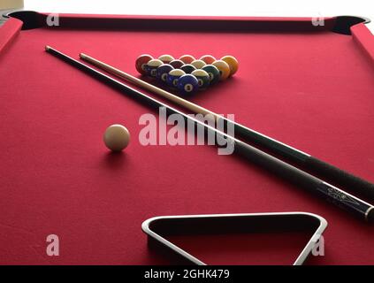 Billiard balls on a red pool table with two cues, ball rack and cue ball Stock Photo