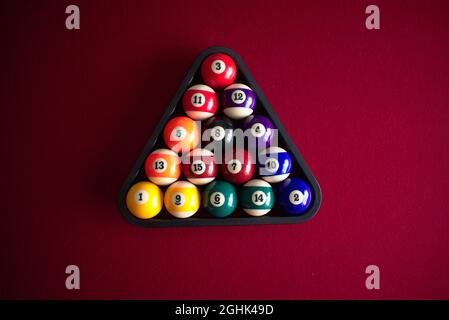 Numbered pool balls in a ball rack on a red billiards table Stock Photo