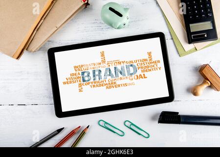 Brand word cloud on tablet. Office supplies on a white table. Stock Photo
