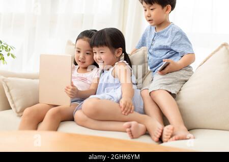 Cute children using digital tablet on sofa Stock Photo