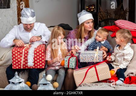 happy family sitting on the couch in the living room and unpacking Christmas presents, the concept of a family holiday Stock Photo