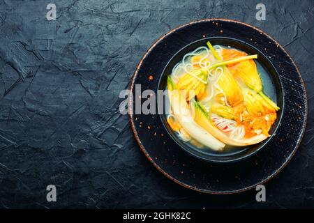 Soup with rice noodles and dumplings in pumpkin flowers Stock Photo