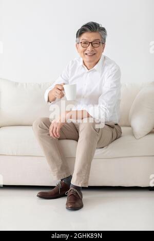 Cheerful senior man drinking coffee at home Stock Photo