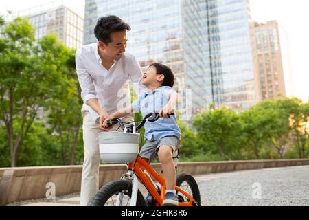Happy young father teaching son to ride bike Stock Photo