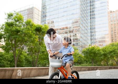 Happy young father teaching son to ride bike Stock Photo