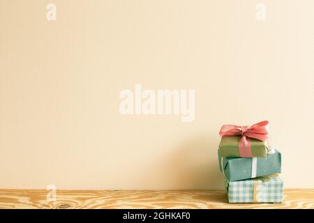 Stack of green gift boxes on wooden table. beige wall background Stock Photo