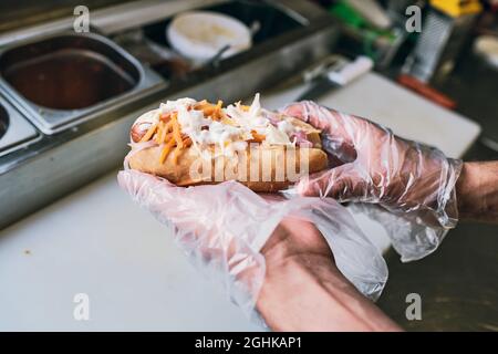 Gloved hands of young man holding fresh fast food before giving it to buyer Stock Photo