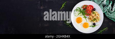 Breakfast with zucchini waffles, fried eggs, tomato, black olives and arugula on white background. Appetizers, snack, brunch. Healthy vegetarian food. Stock Photo