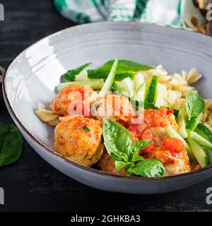 Italian pasta. Fusilli with meatballs, cucumber and basil on dark background. Dinner. Slow food concept. Stock Photo