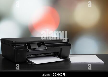 Compact laser printer on black desk against blurred background Stock Photo