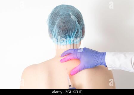 The doctor makes an anesthetic procedure for a girl a subcutaneous medical blockade with hormones to relieve anesthesia and relieve inflammation at th Stock Photo