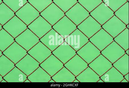 Rusty chain link fence on green blur background, shallow focus Stock Photo