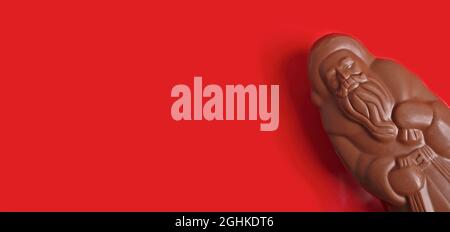 Delicious chocolate santa claus on red background. Panoramic image with copy space. Stock Photo