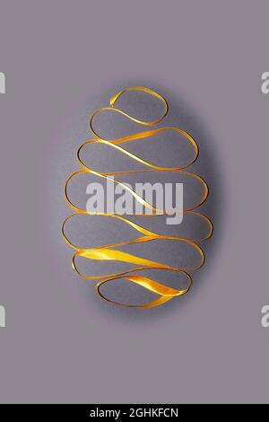 Close up Easter egg made of yellow ribbon on grey background. Trendy Easter composition. Happy Easter greeting card. Copy space for text. Minimal East Stock Photo