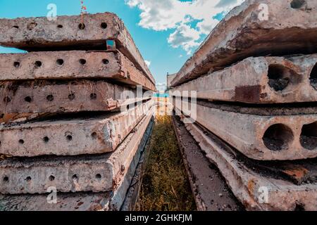 Used concrete slabs lay on top of each other near an industrial area. Stock Photo