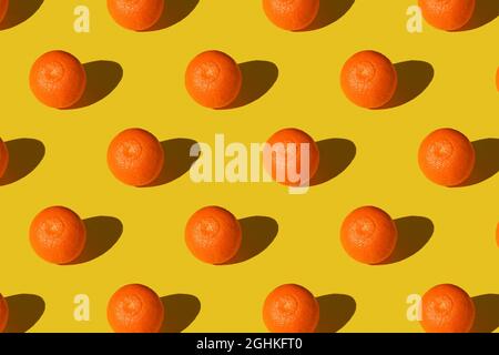 Trendy summer Seamless pattern of juicy orange manadarin tangerine with shadow on sunlight yellow background. Minimal summer rest concept. Healthy foo Stock Photo