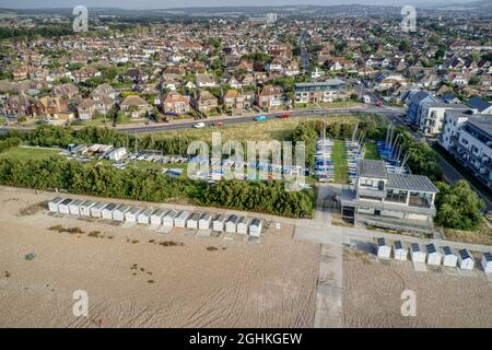 Worthing Yacht Club with beach huts in view along the Goring by Sea seafront. Aerial view. Stock Photo