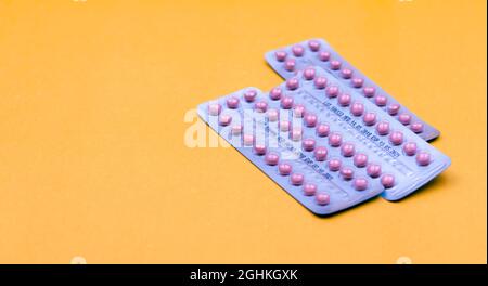 Blister packs of contraceptive pills on yellow background. Hormone pills for treatment hormone acne. Birth control pills. Estrogen and progesterone Stock Photo