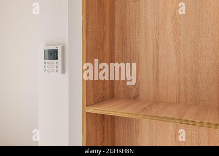Climate control panel on the wall in a room with wooden built-in furniture with shelves Stock Photo