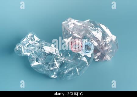 Composition of two used crushed plastic bottles on the blue background. Recycling concept. Stock Photo