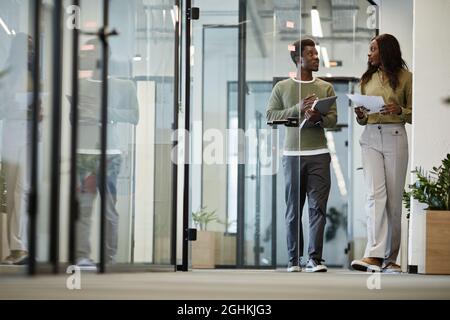 Business people walking down office corridor and discussing details of project they are working on Stock Photo
