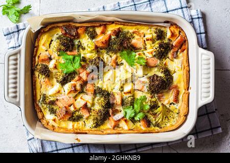 Quiche pie with salmon and broccoli in baking dish, top view. Stock Photo