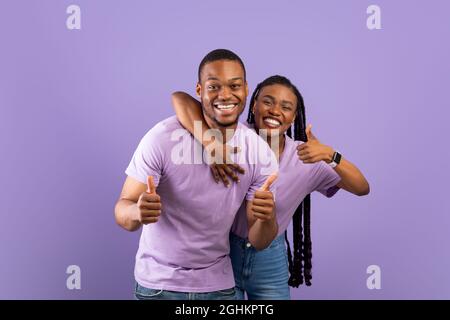 Happy black couple gesturing thumbs up and smiling Stock Photo
