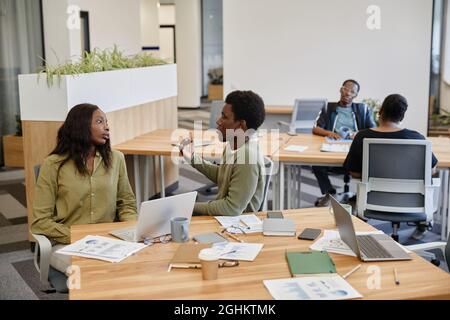 Tired young businesswoman listening to coworker trying to prove his point in conversation about new strategy of company development Stock Photo