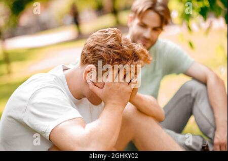 Guy hiding his face behind hands and friend Stock Photo
