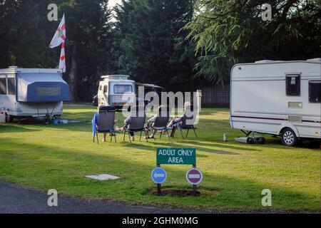 Caravanners relax in the evening sun on the adults only section on a campsite, Stanmore Hall Touring Park, Bridgnorth, Shropshire Stock Photo