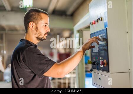 Close-up detail view of professional worker technician machinist work on control panel in factory production workplace. Industrial working operating p Stock Photo