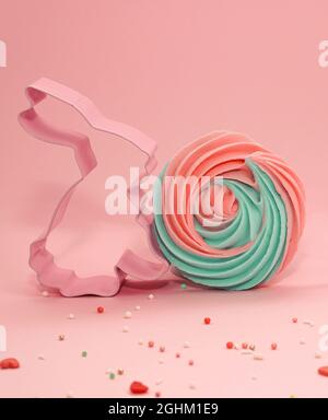 Easter pastel colored Cookie Cutter on pink pastel background. Easter Bunny with mint blue and pink meringue. Sweet candy concept. Happy Easter Day co Stock Photo