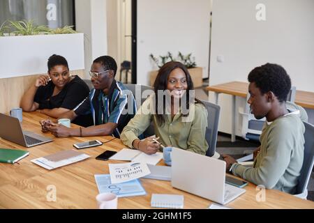 Positive young African-American business people talking at big meeting table Stock Photo